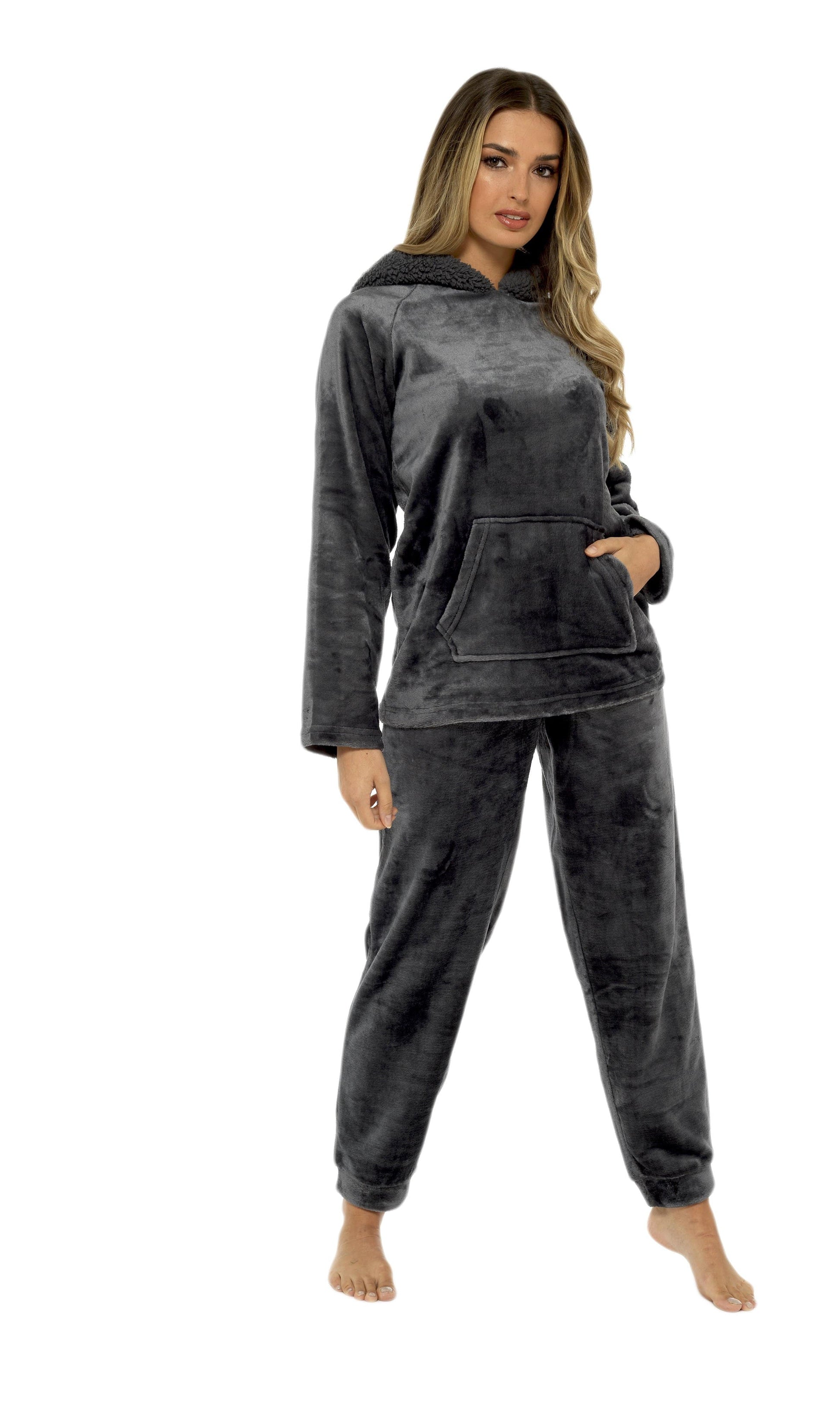 Woman wearing a dark gray hoodie and pants set on a white background