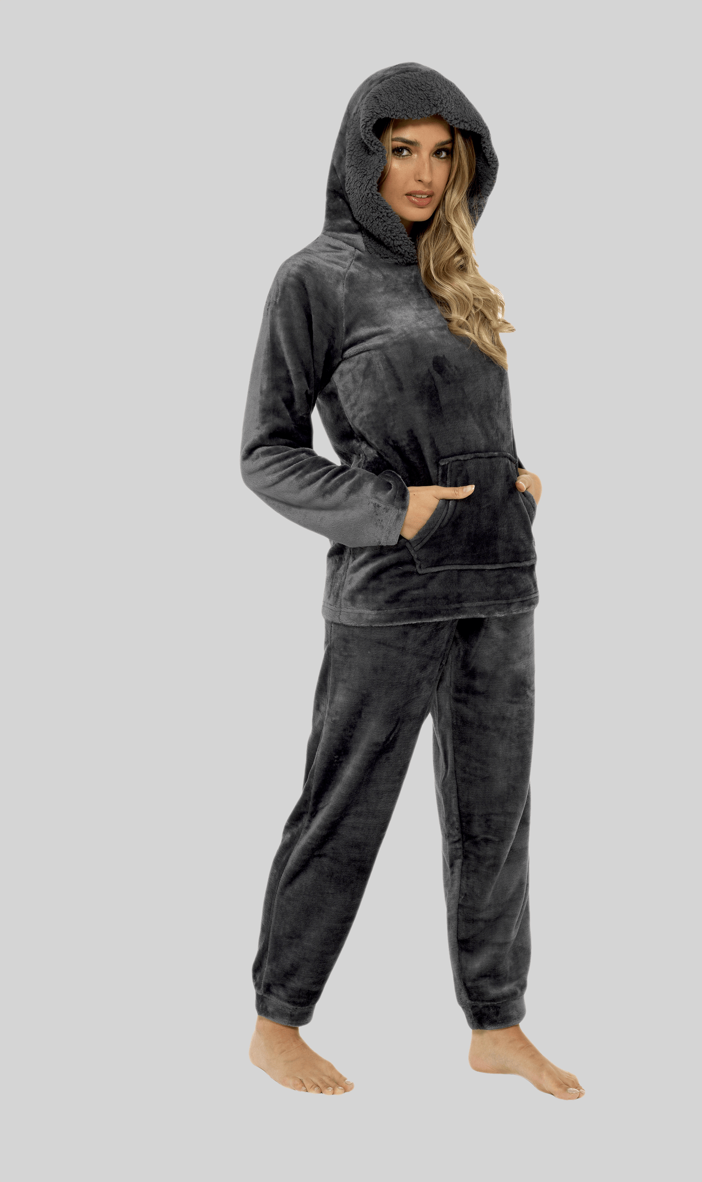 Woman wearing a gray hoodie and sweatpants set on a light gray background