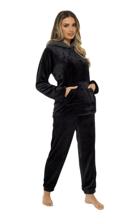 Woman wearing a black velour hoodie and pants set on a white background