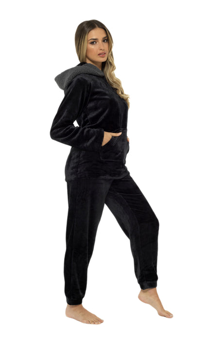 Woman wearing a black velour hoodie and pants on a white background